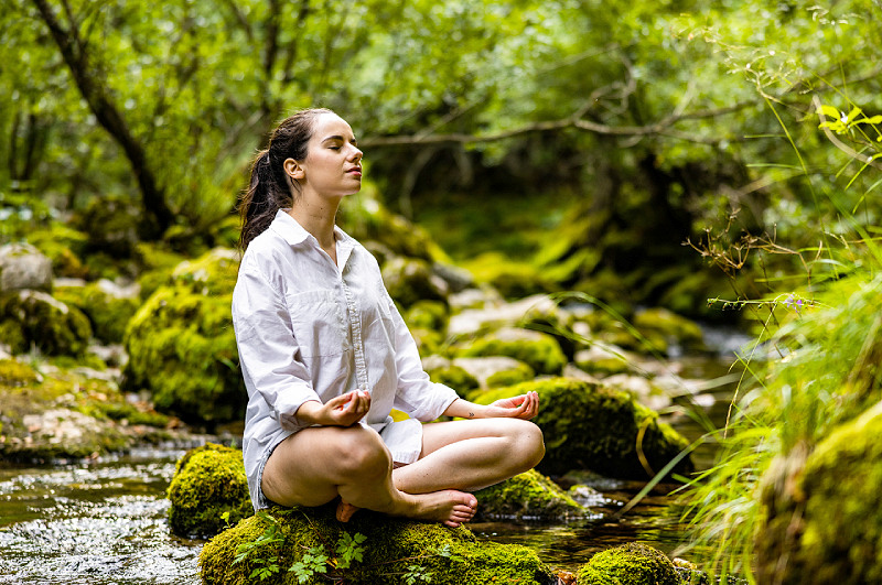 entspannungstherapie Frau sitzt im Wald in Yoga pose